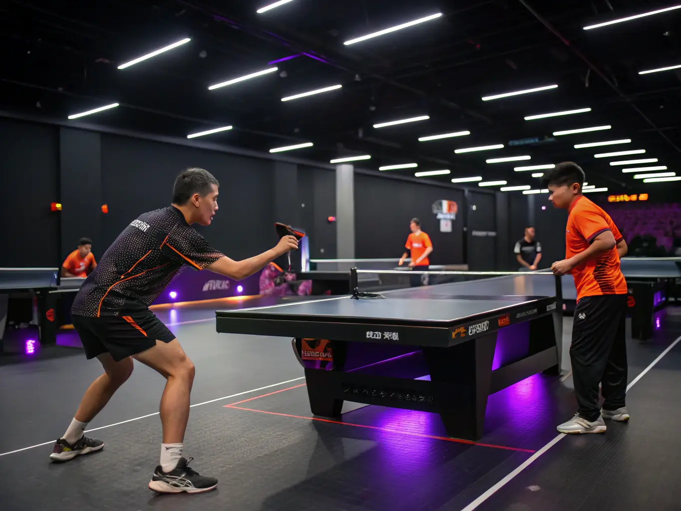 A dynamic shot of table tennis players engaged in a training session, focusing on technique and skill development, with a coach providing guidance in the background. The setting is a well-lit, modern sports hall.